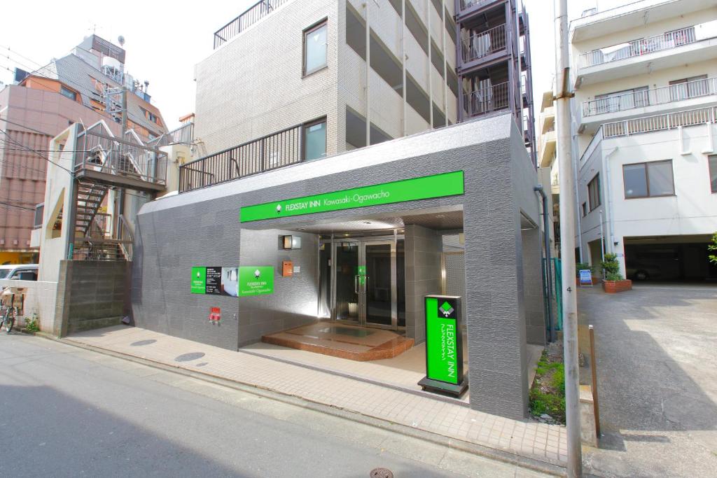 a building with a green sign on the side of a street at FLEXSTAY INN Kawasaki Ogawacho in Kawasaki