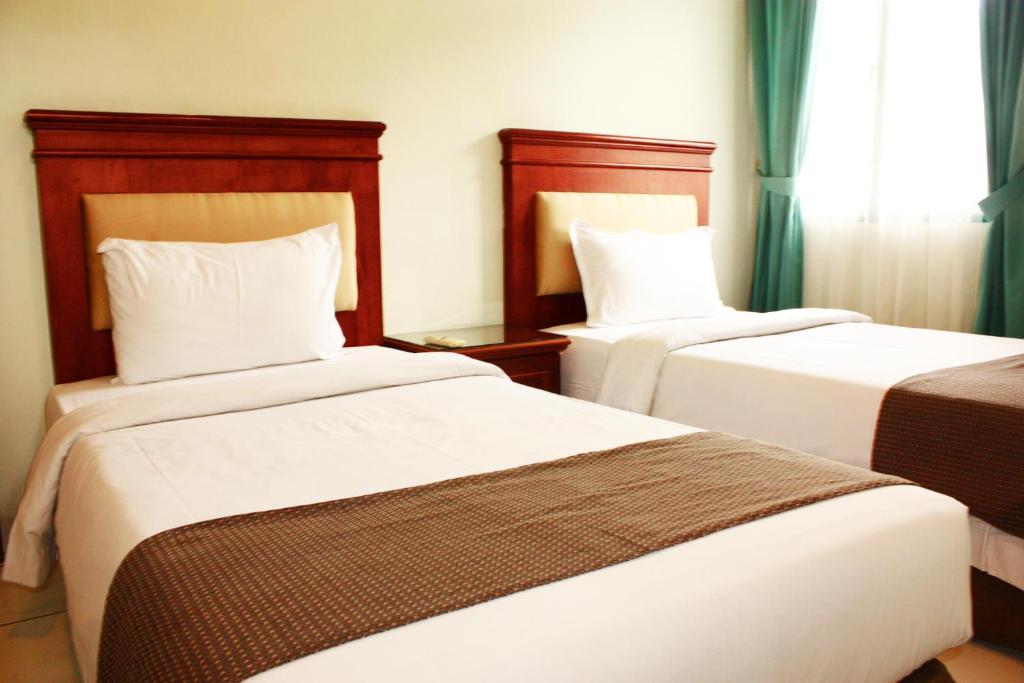 a hotel room with two beds and a window at Travellers Suites Serviced Apartments in Medan