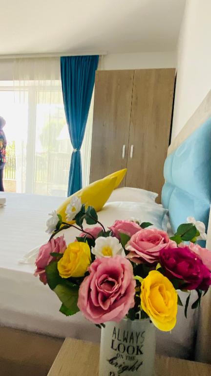 a bouquet of flowers in a vase on a bed at Pensiunea CASID in Eforie Nord