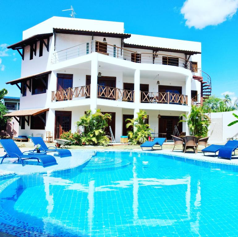 a villa with a swimming pool in front of a building at Hotel e Pousada Cumbuco Guesthouse in Cumbuco