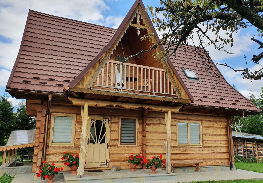 a log cabin with a balcony and a deck at Domek Agroturystyczny na Putówce in Słopnice