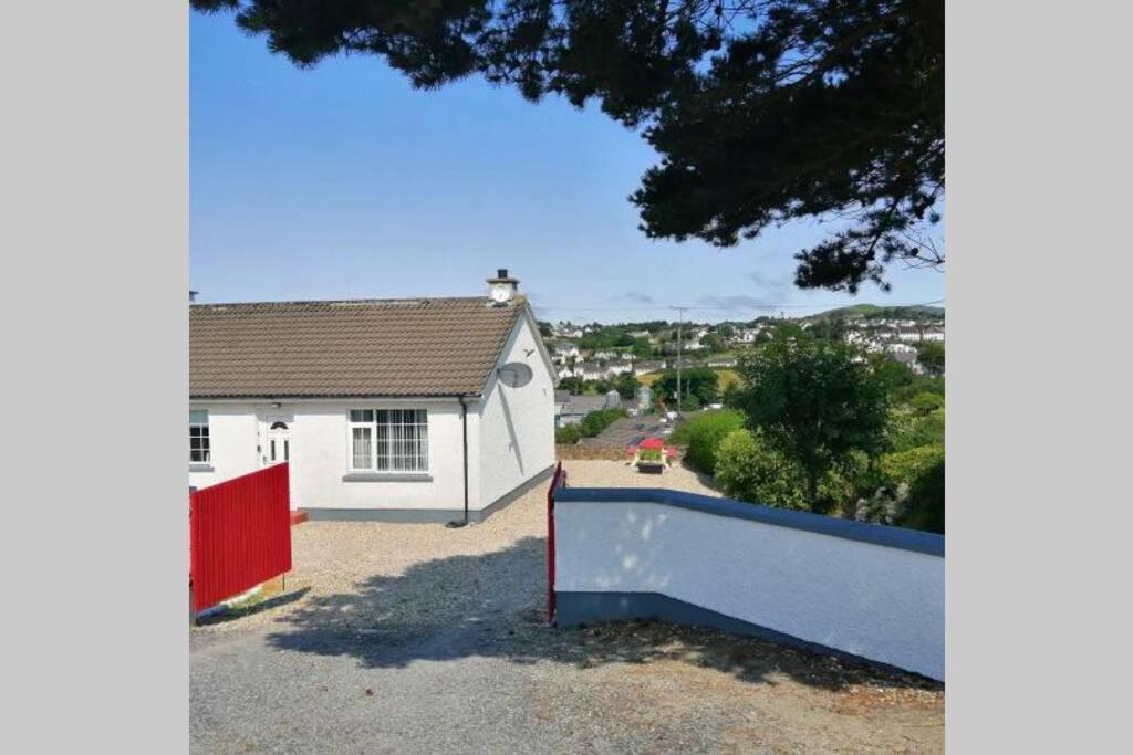 a white house with a red fence in front of it at Red Gate Cottage in Buncrana