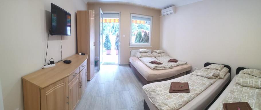 Pokój z 2 łóżkami i biurkiem z telewizorem w obiekcie Relax Beach Apartman w Hajduszoboszlo