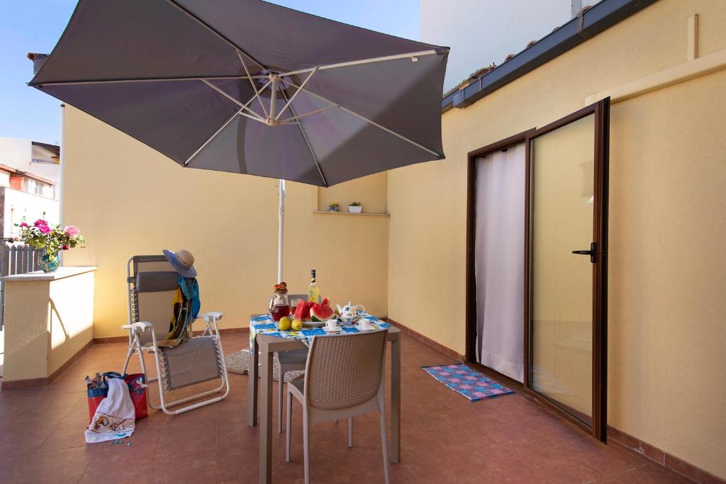 d'une table, de chaises et d'un parasol sur le balcon. dans l'établissement Il Corallo, à Castellammare del Golfo