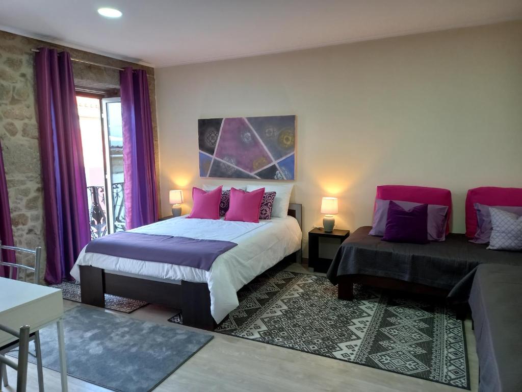 a bedroom with two beds with pink and purple pillows at Rustic House Fundão in Fundão