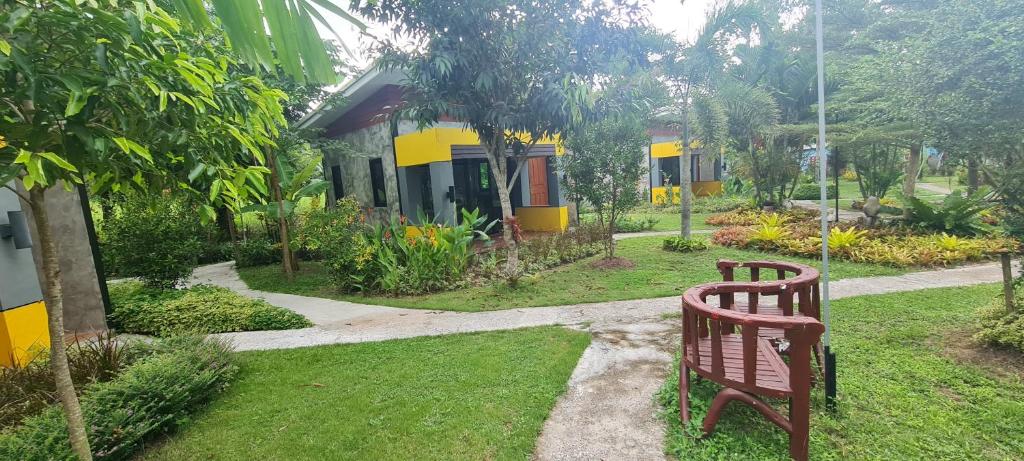 a bench sitting in the grass in front of a house at Nubdao Resort&Restaurant in Nong Prue