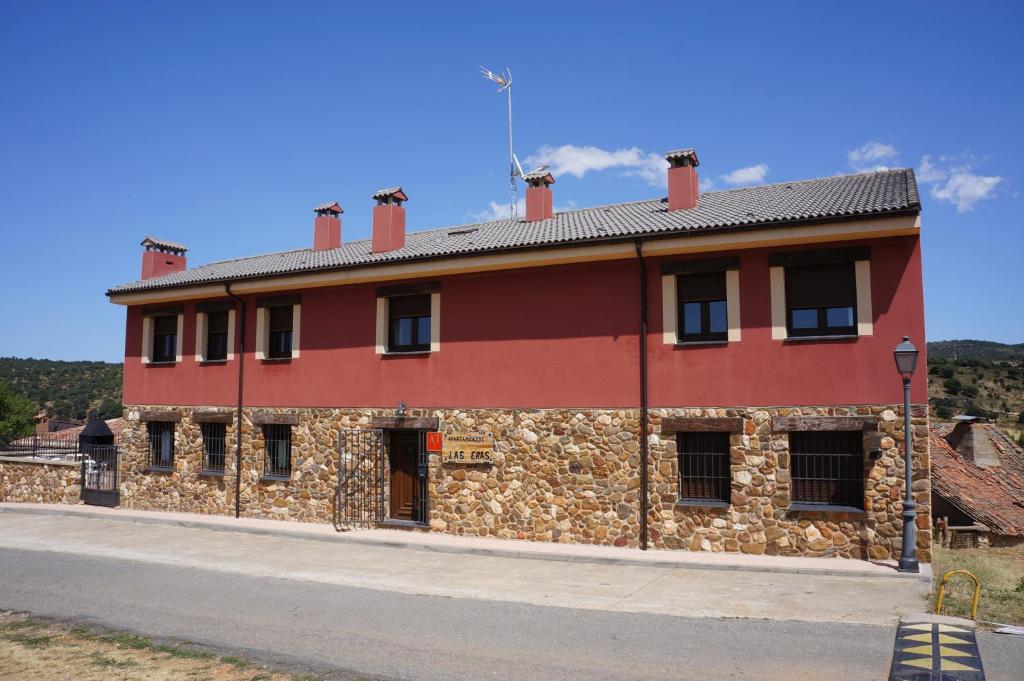 ein großes rotes Gebäude mit einer Steinmauer in der Unterkunft APARTAMENTOS LAS ERAS in El Negredo