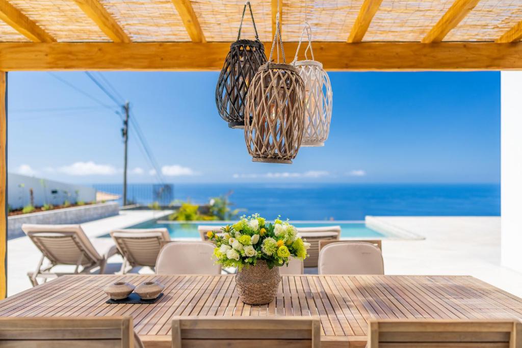 een houten tafel met een vaas met bloemen erop bij Villa Horizonte Azul by Holiday Rental Madeira in Ponta do Sol