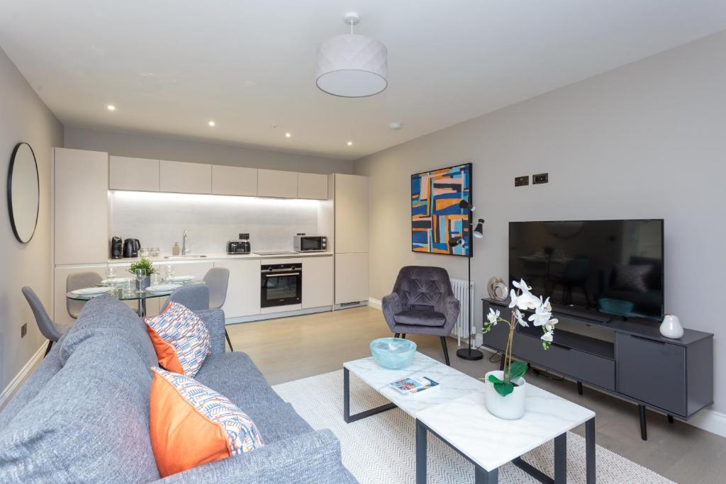 ein Wohnzimmer mit einem blauen Sofa und einem TV in der Unterkunft Dragon Suites - Edinburgh City Centre 2 Bed Apartment in Edinburgh