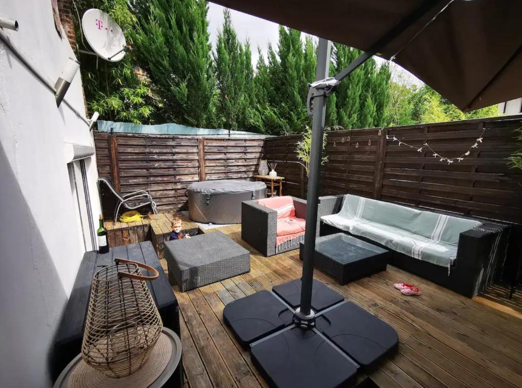 een patio met een parasol en een bank op een terras bij Loft Paris Beach + extérieur #Jacuzzi #Barbecue in Fontenay-sous-Bois
