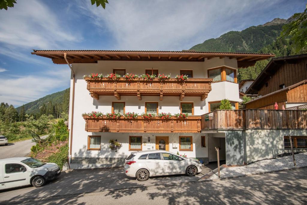 budynek z dwoma samochodami zaparkowanymi przed nim w obiekcie Ferienwohnungen Mischbach w Neustift im Stubaital
