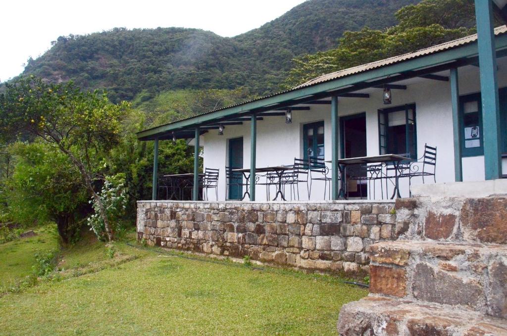 a building with a stone wall next to a mountain at Sir John's Bungalow in Matale
