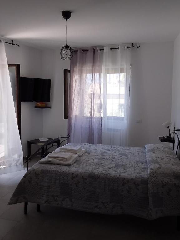 Primae Noctis Apartments في Roccascalegna: غرفة نوم بيضاء بها سرير ونافذة
