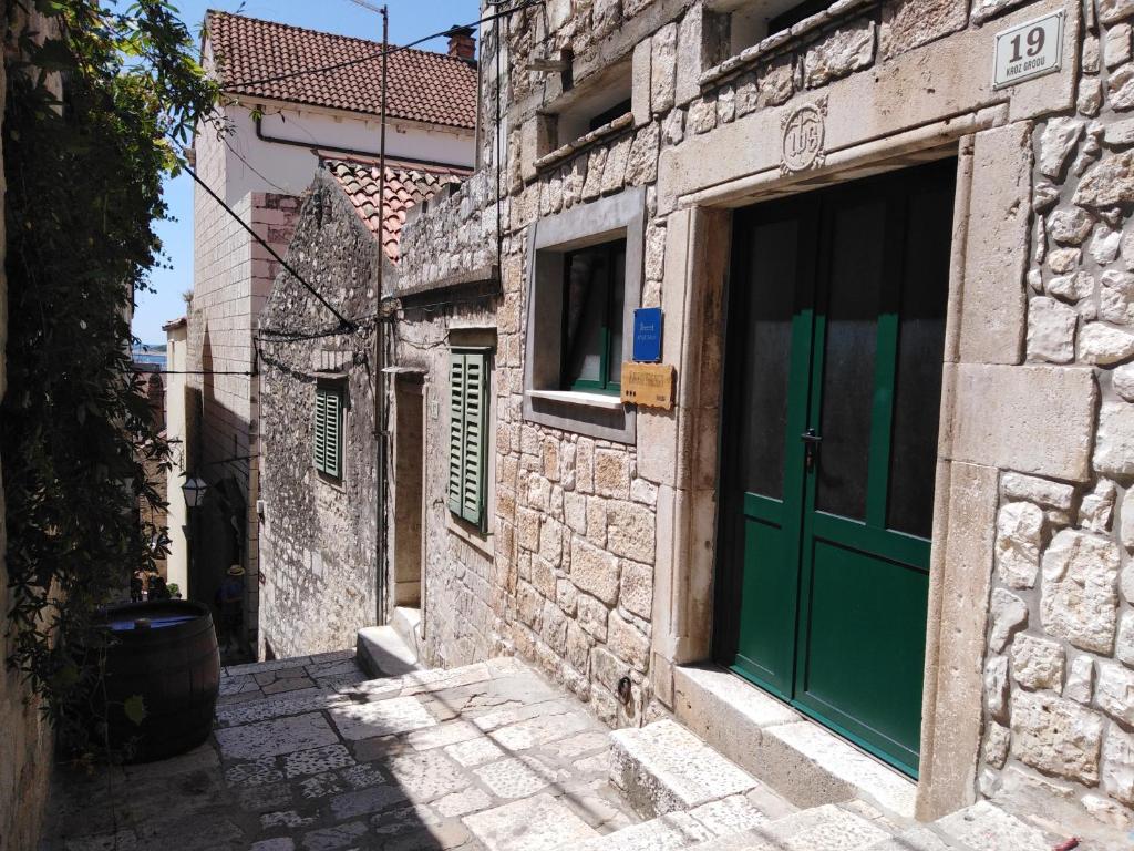 an alley with a green door on a stone building at Apartment Bibić - Hvar center old town in Hvar