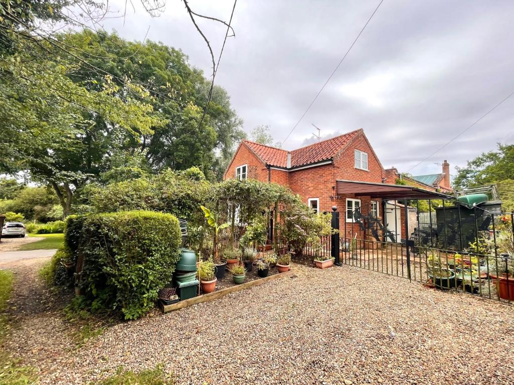 a brick house with plants in pots in front of it at Willow Cottage on the upper River Bure in Aylsham