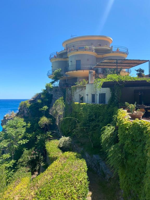 a house on the side of a hill next to the ocean at Villa Alcado in Copanello