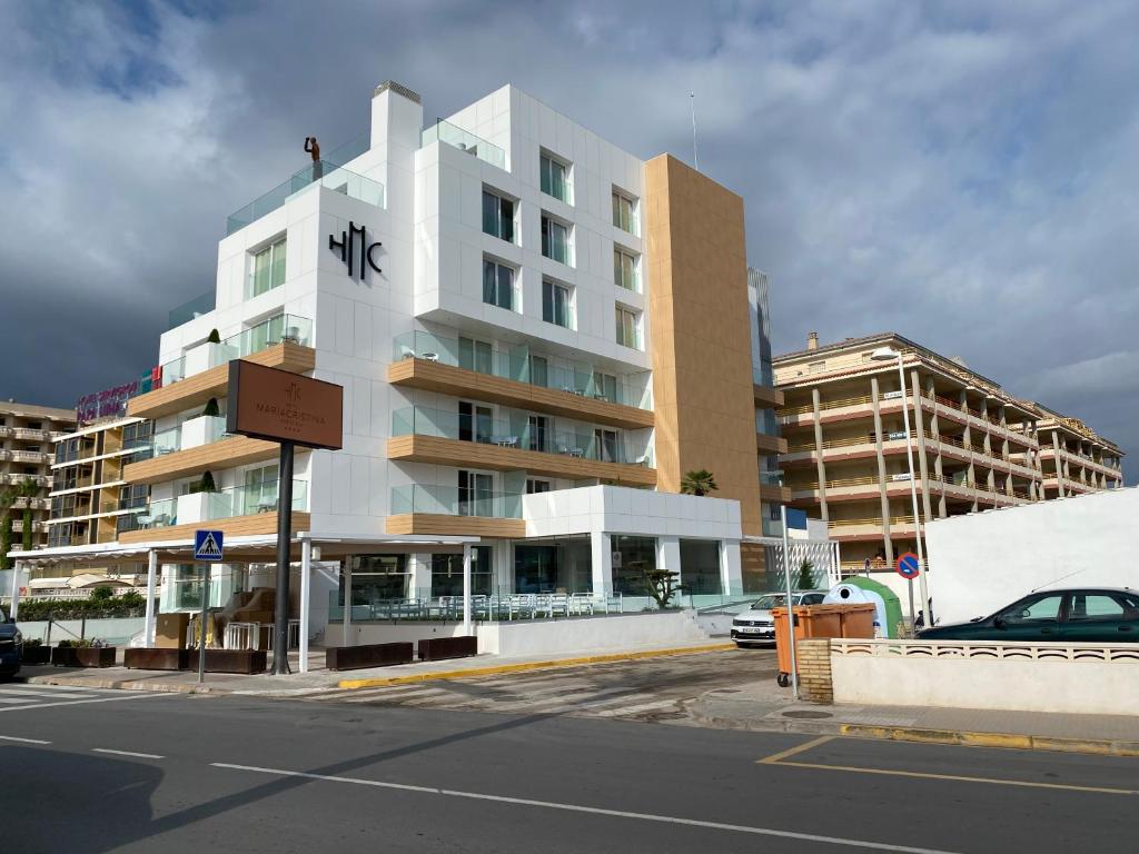 un edificio blanco alto con un cartel delante en Hotel María Cristina, en Peñíscola