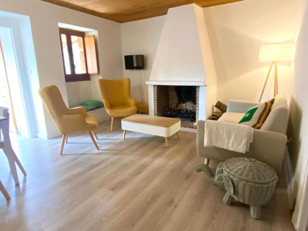 een woonkamer met een bank en stoelen en een open haard bij Apartamento rural Meaus in Rubiás