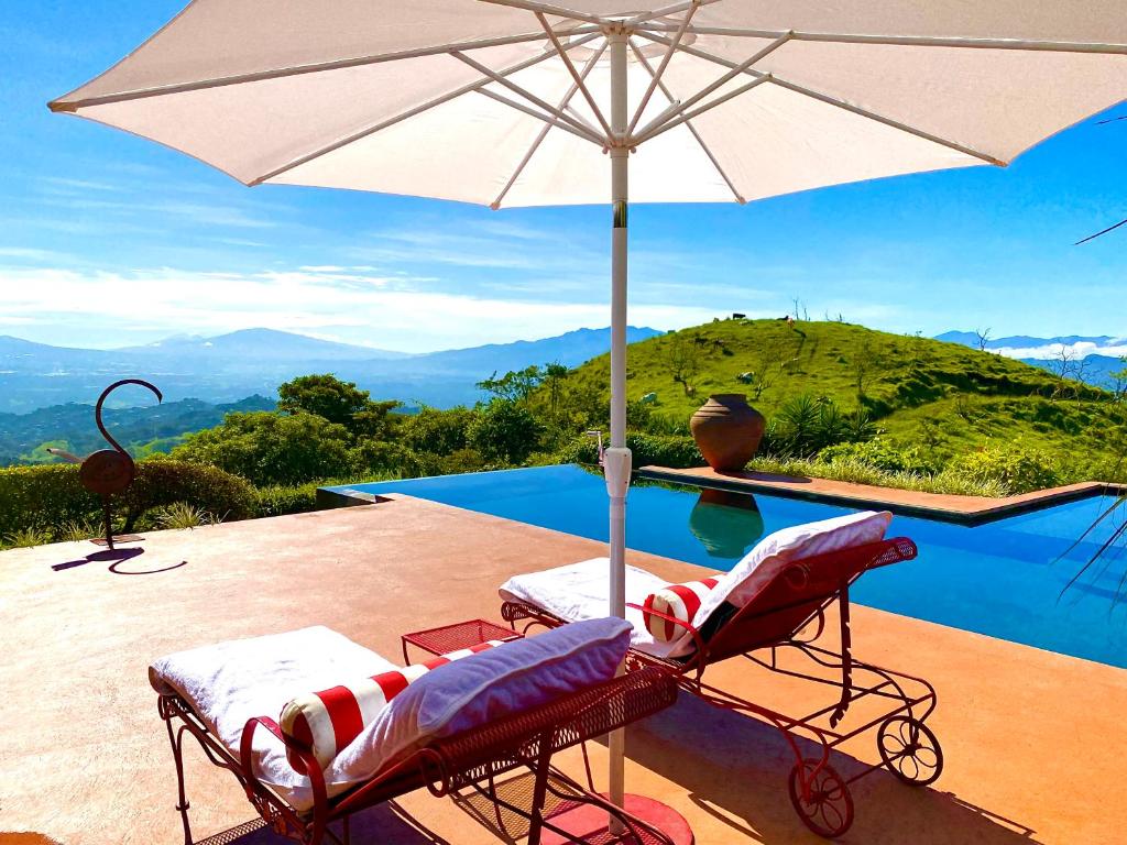 - Piscina con 2 sillas y sombrilla en Magic Mountain Views Villa, en Atenas