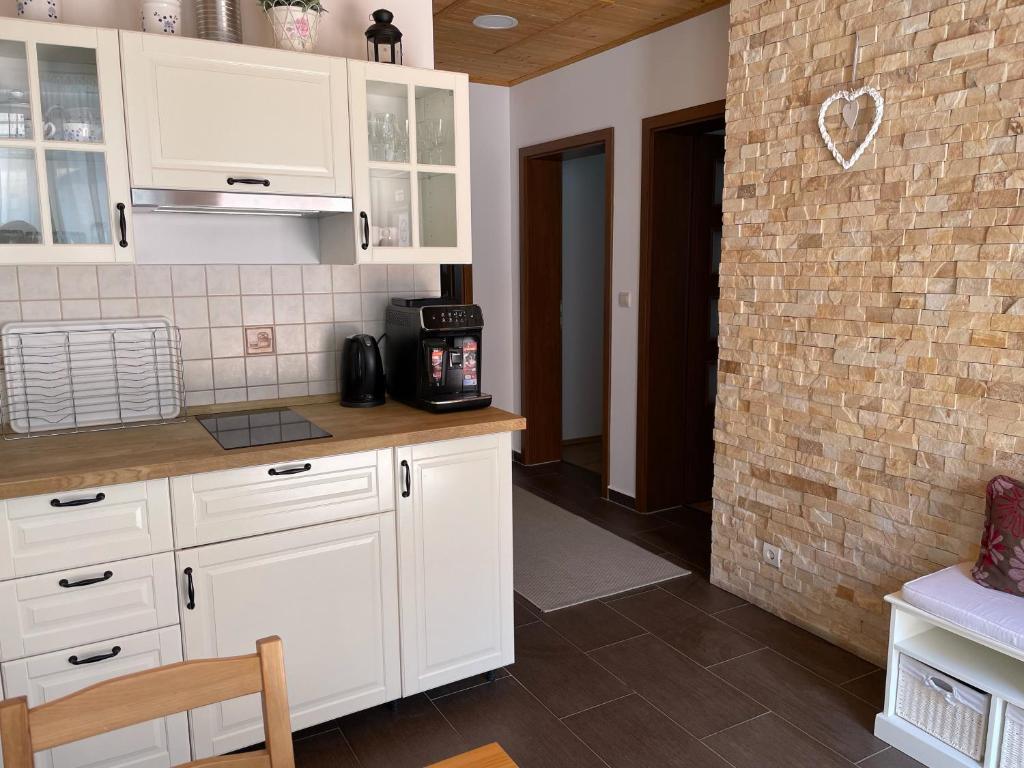 een keuken met witte kasten en een bakstenen muur bij CORNER Vendégház in Veszprém