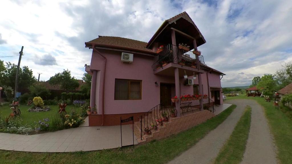 a pink house with a balcony on a dirt road at PENSIUNEA OANA in Balc