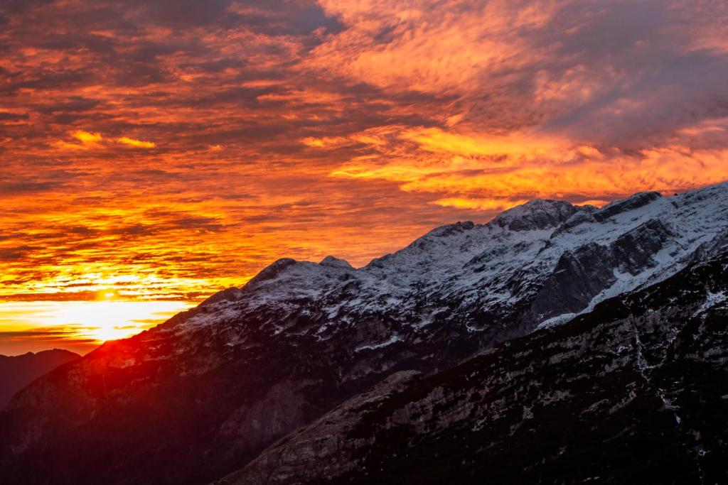a sunset on top of a snow covered mountain at Apartma TOBI in Bovec