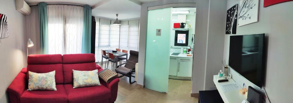 uma sala de estar com um sofá vermelho e uma cozinha em El Balconcito de San Millan em Segóvia