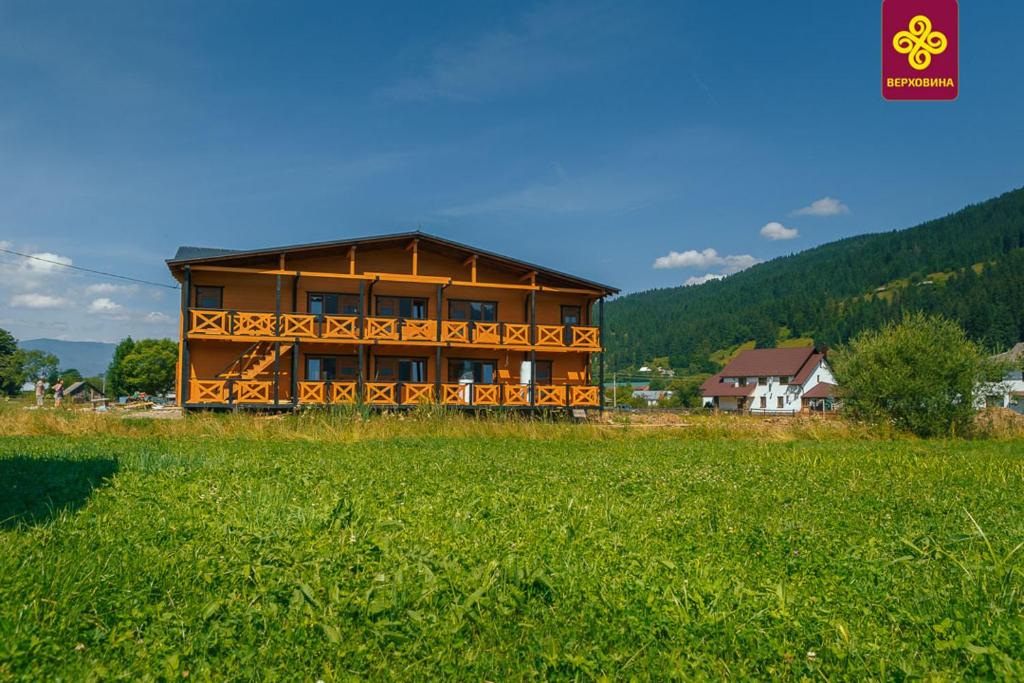 a large wooden house in a field of grass at На Ґанку in Verkhovyna