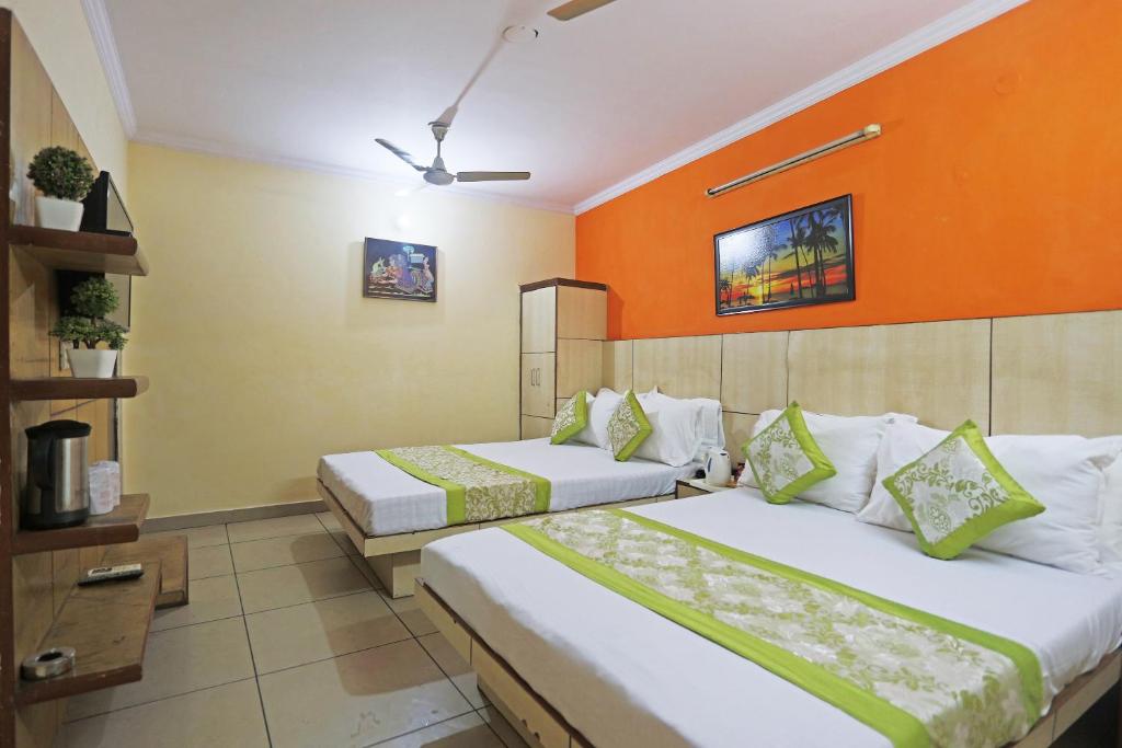 2 łóżka w pokoju z pomarańczową ścianą w obiekcie Hotel Sun Village Near New Delhi Railway Station w Nowym Delhi
