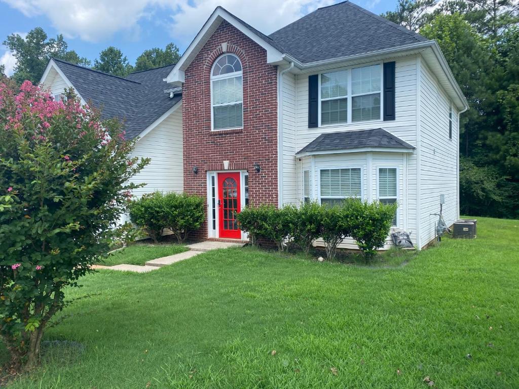 une maison avec une porte rouge dans une cour dans l'établissement CLOSE TO ATLANTA & SIX FLAGS, à Villa Rica