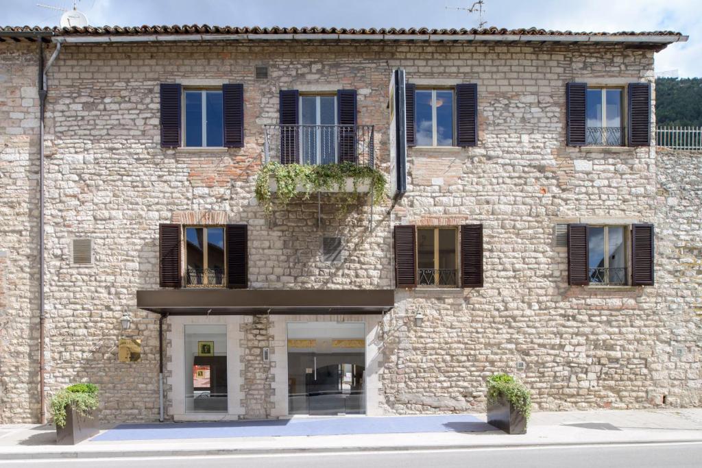 un grande edificio in mattoni con finestre e piante di Hotel San Francesco e il lupo a Gubbio