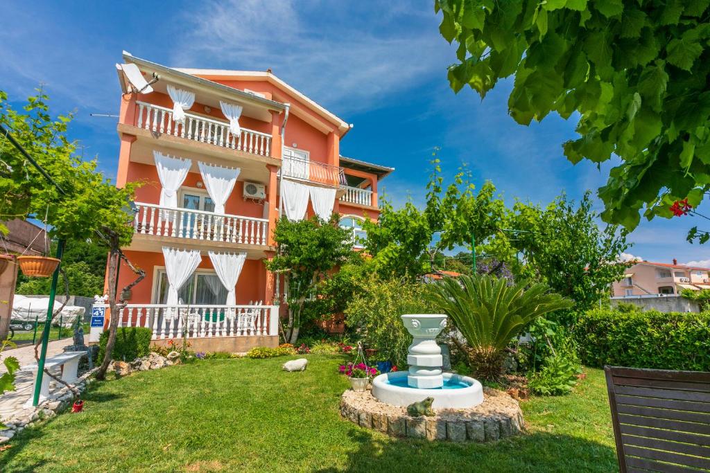 una casa con un jardín delante de ella en Apartments Lino, en Lopar