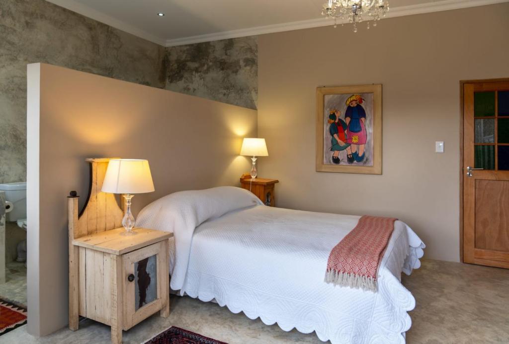 a bedroom with a bed and a lamp on a table at Jeffreys Guest Rooms in Jeffreys Bay