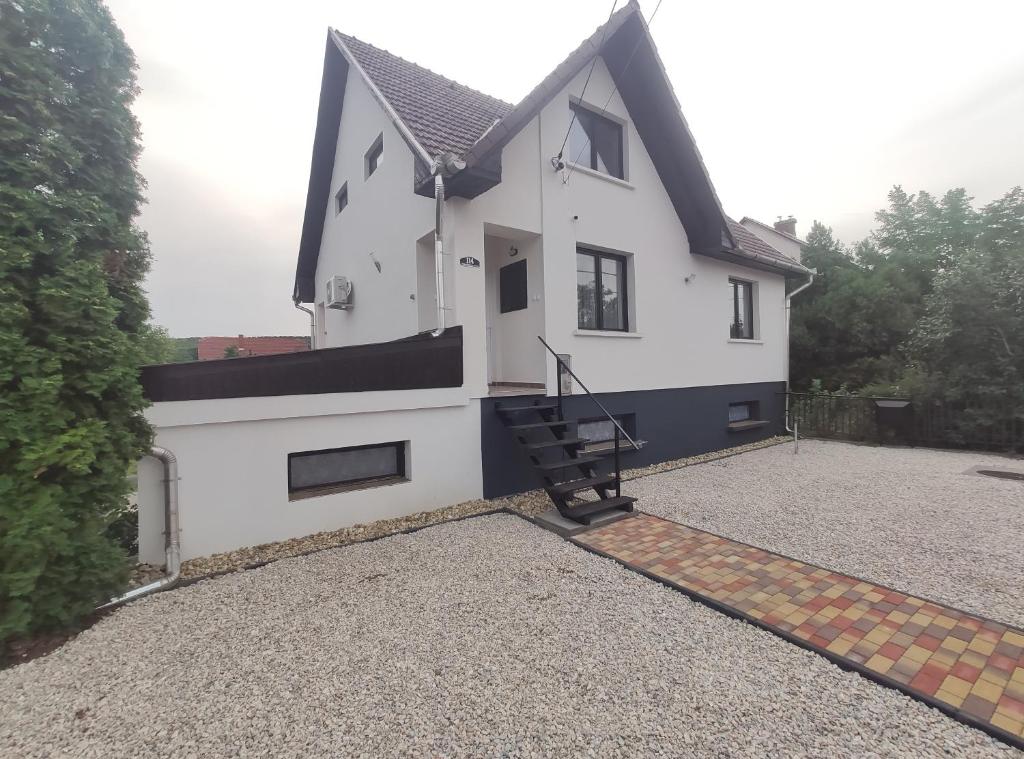 Casa blanca con techo negro y entrada en Artemis Vendégház, en Bogács