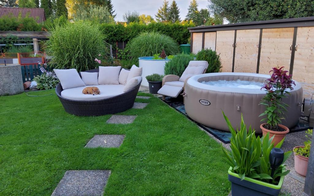 a backyard with a hot tub and a dog laying on the grass at Ferienwohnung am Thayatalradweg in Schwarzenau
