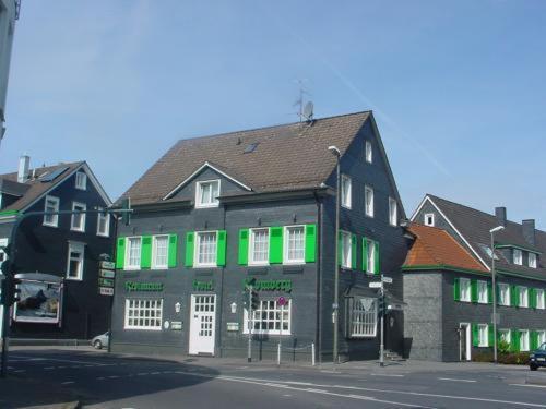 a building with green shutters on a street at Hotel Restaurant Kromberg in Remscheid