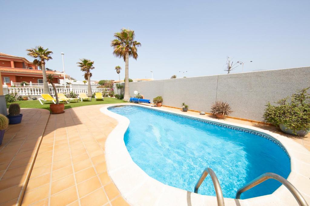 a swimming pool in front of a building with palm trees at MEDANO4YOU Casa Girasol in El Médano