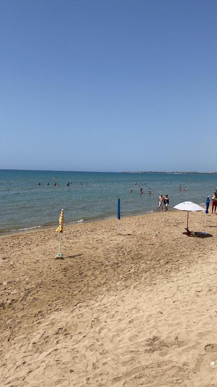 una playa con gente nadando en el agua en Villa Berenice, en Pachino