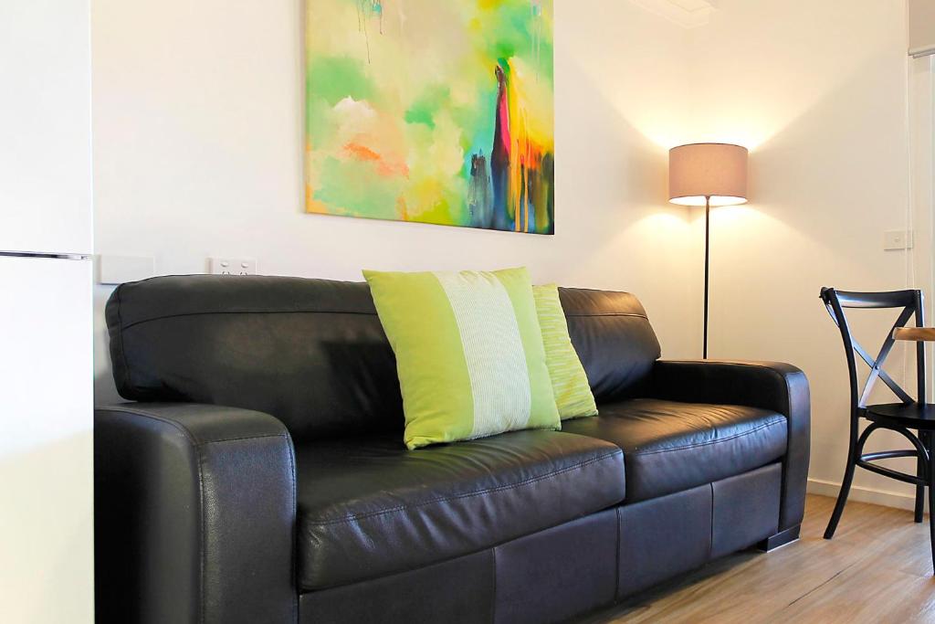 czarna skórzana kanapa z żółtą poduszką w obiekcie Apartments 521 w mieście Warrnambool