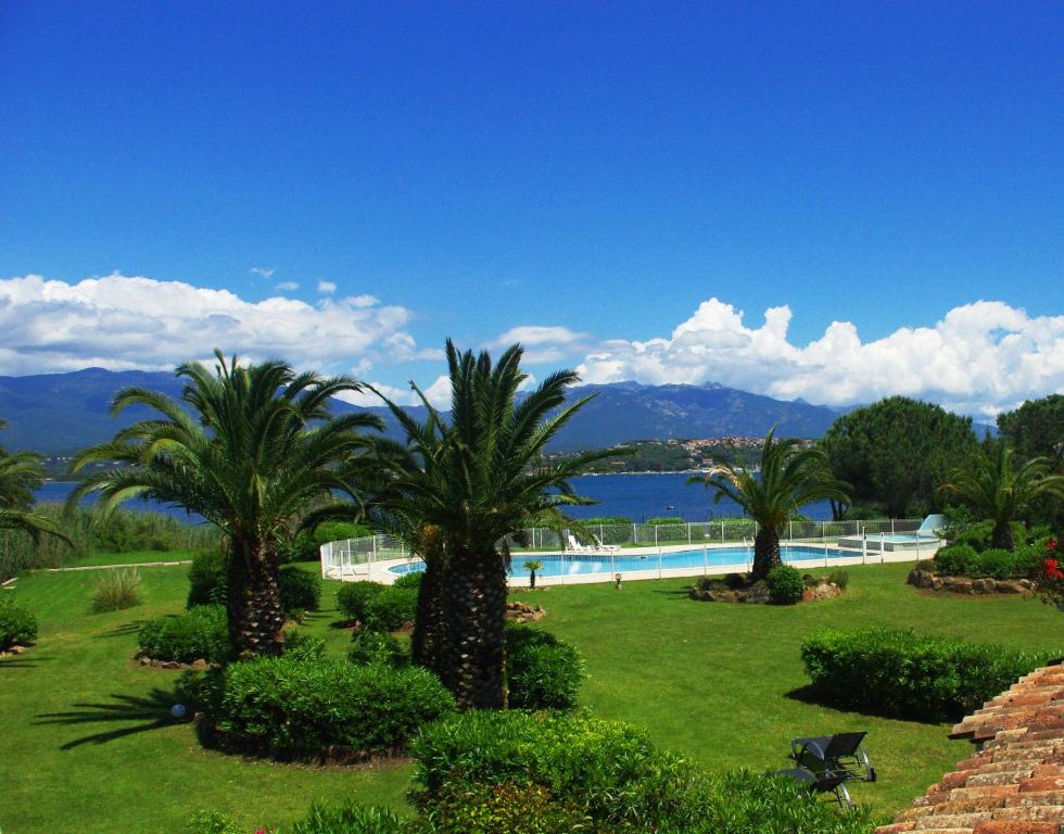 um resort com palmeiras e uma piscina em Résidence Le Village Marin em Porto-Vecchio
