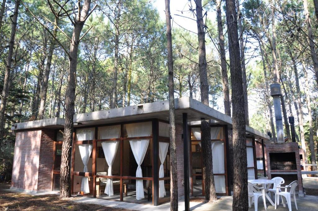 una cabaña en el bosque con mesa y sillas en Cabañas Abril en Mar de las Pampas