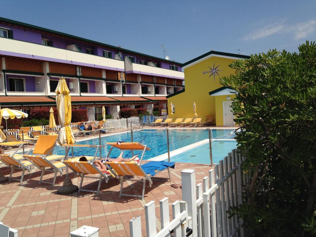 a hotel with a swimming pool with chairs and umbrellas at Villaggio Margherita in Caorle