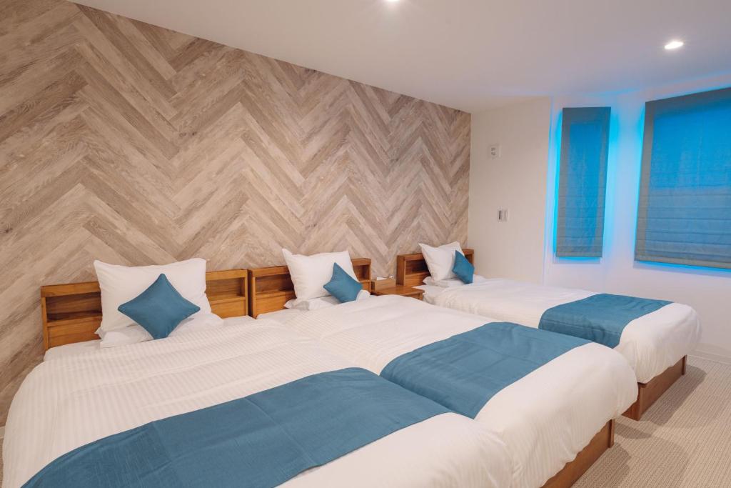 two beds in a room with wooden walls at Hotel Santa Barbara Miyakojima Resort in Miyako-jima