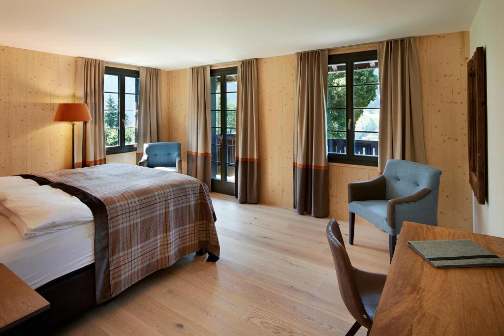 ein Hotelzimmer mit einem Bett, einem Tisch und Stühlen in der Unterkunft Eiger View Alpine Lodge in Grindelwald