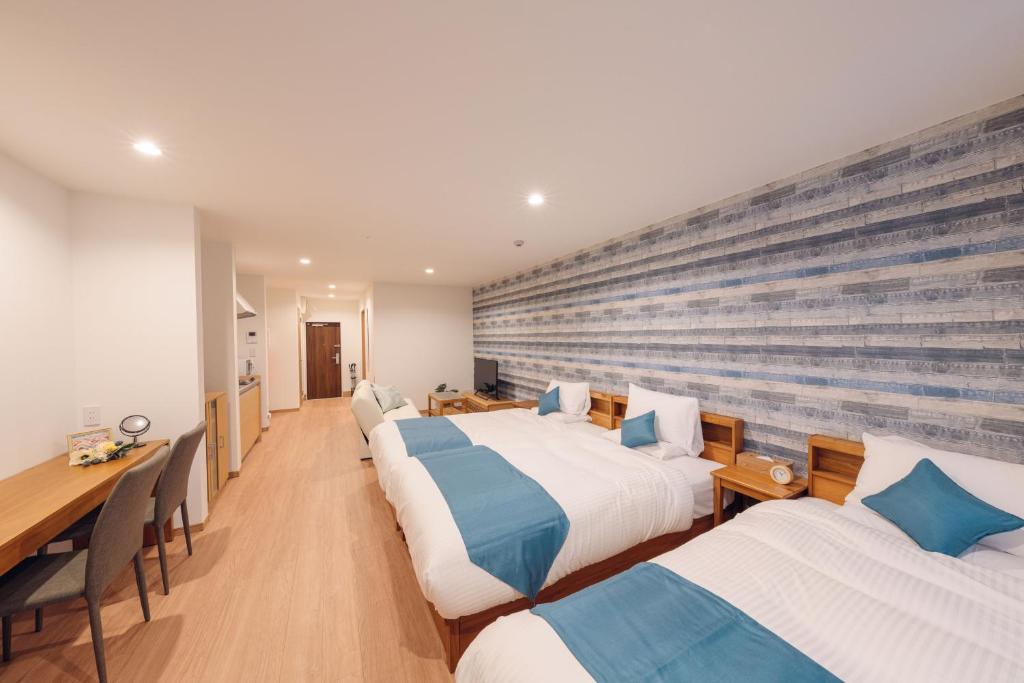 a hotel room with three beds and a table at Hotel Santa Barbara Miyakojima Resort in Miyako-jima