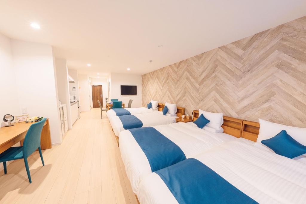 a hotel room with three beds and a desk at Hotel Santa Barbara Miyakojima Resort in Miyako-jima