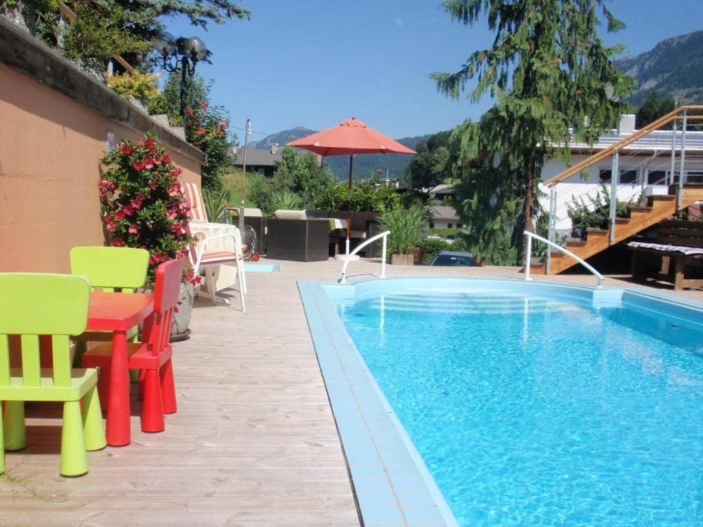 una piscina con sedie colorate e un tavolo accanto ad essa di Hotel Metzgerwirt a Fieberbrunn