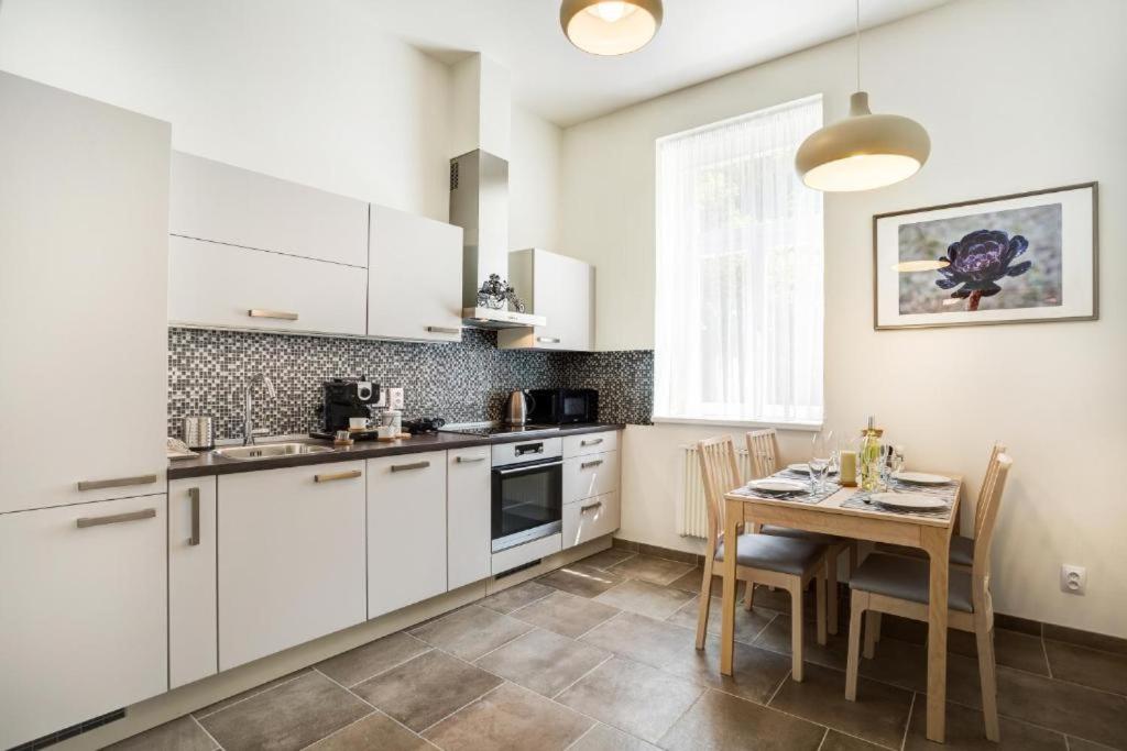kuchnia z białymi szafkami i stołem z krzesłami w obiekcie Apartman Karlovarská w Mariańskich Łaźniach