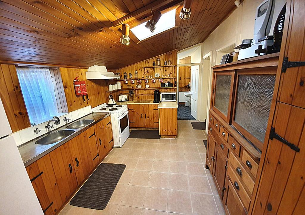 een grote keuken met houten kasten en een wastafel bij Miss Mabel Cottage in Burra