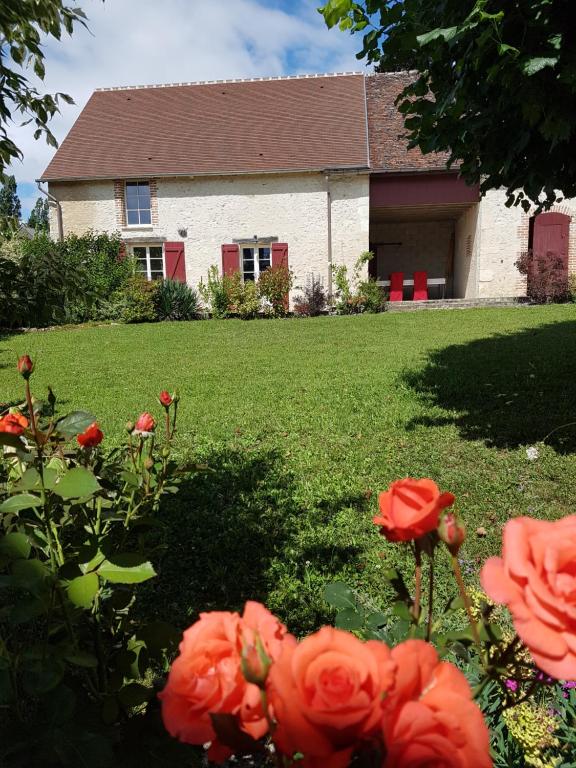 uma casa com rosas vermelhas em frente a um quintal em Les 7 tilleuls - Gîte em Mesland